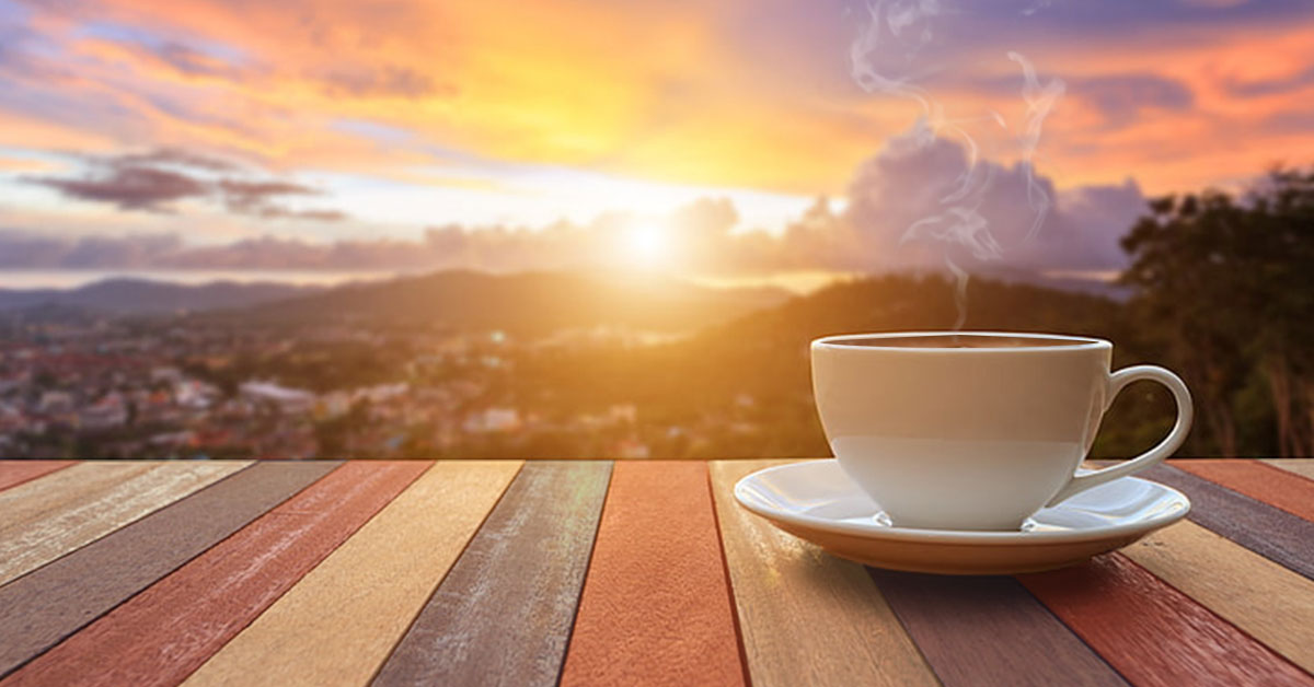 Mission and Vision - photo of a steaming cup of coffee outdoors with a view of the sunrise. Coffee Party USA.